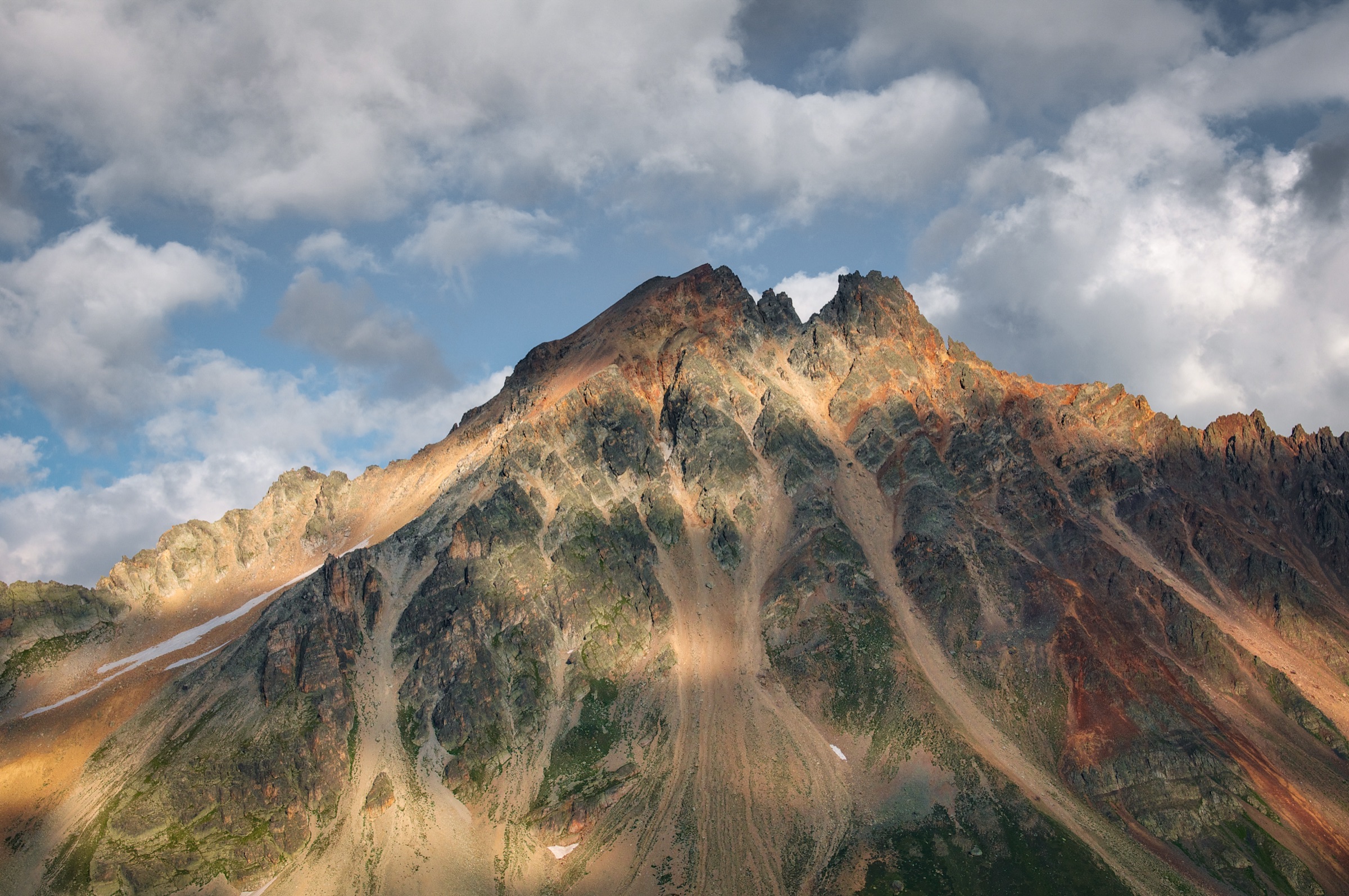 Rocky ridge lit by the sun, under the clouds